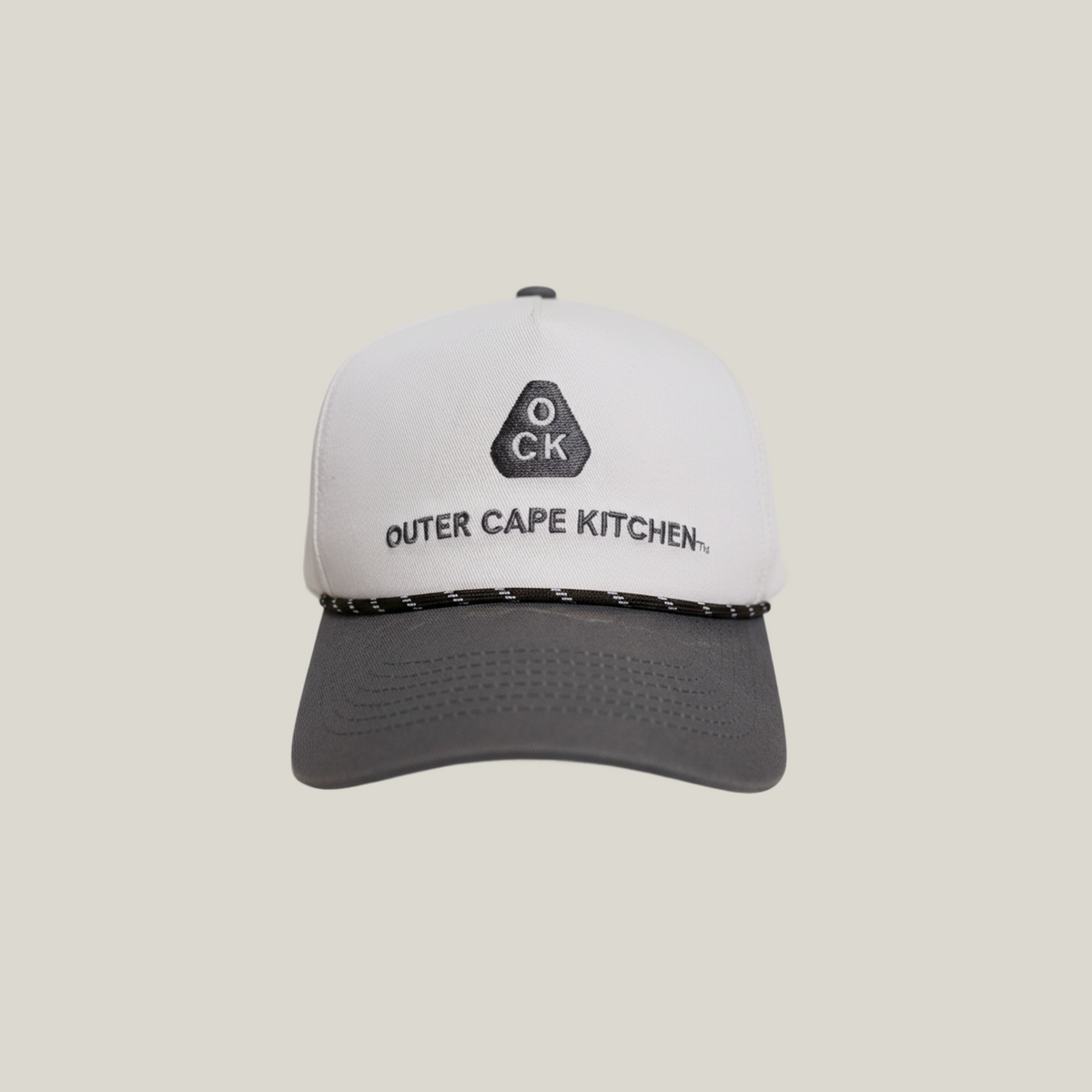 White and gray cap with 'Outer Cape Kitchen' logo on a beige background