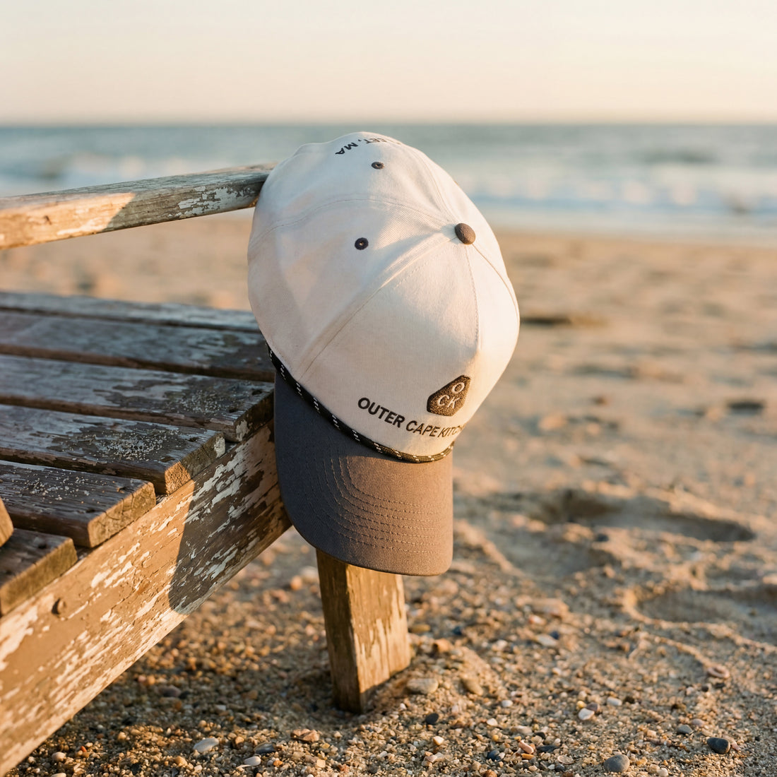 Cap hung on a wooden bench on the beach by the ocean