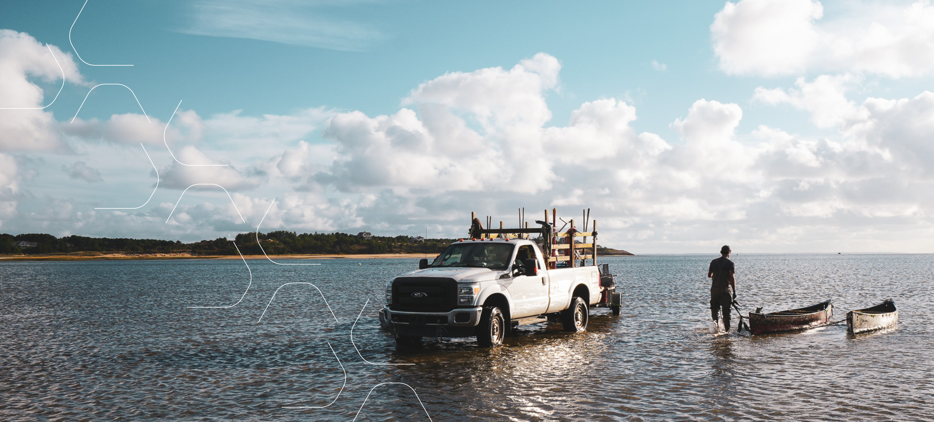 A white pickup truck launching shellfish farming gear into the bay, with a skiff and fisherman at the water’s edge.